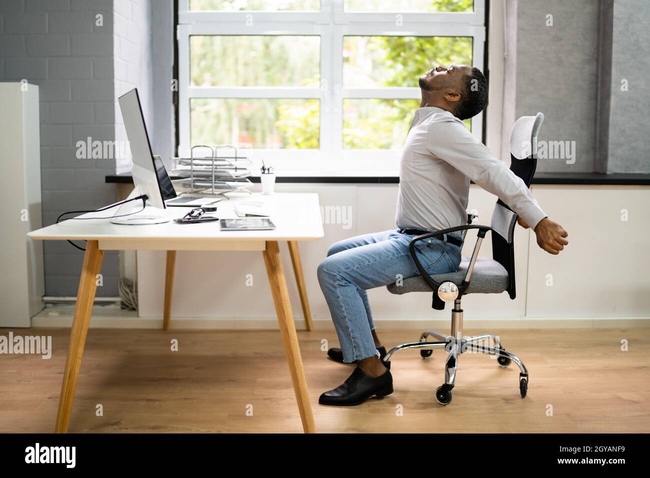 Employé s'étendant au bureau au travail Banque D'Images