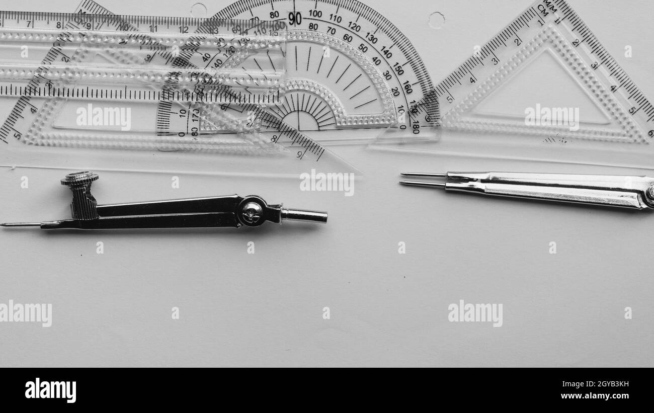 Outils de mesure géométrique, éléments de dessin et instruments mathématiques placés sur une feuille de papier blanc. Retour à l'école et formation en génie b Banque D'Images