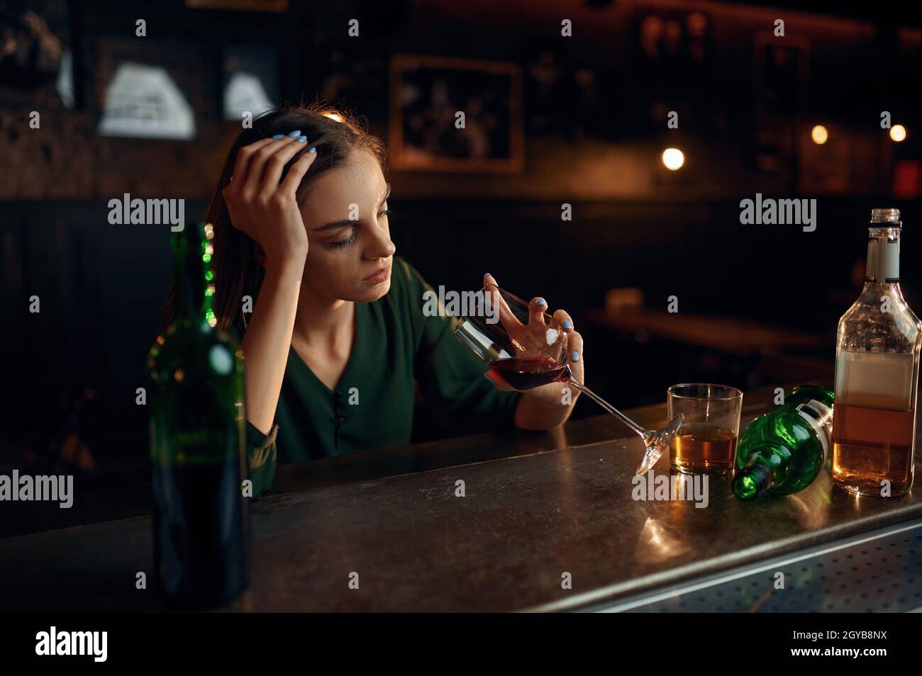 Une femme malheureuse boit une boisson alcoolisée au comptoir du bar.Une femme au pub, émotions humaines, activités de loisirs, dépression Banque D'Images