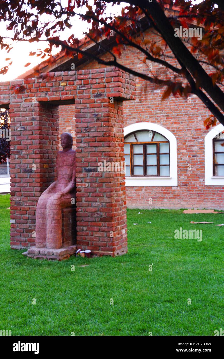 Femme surréaliste assis sculpture et mur de briques à l'arrière-plan extérieur Banque D'Images