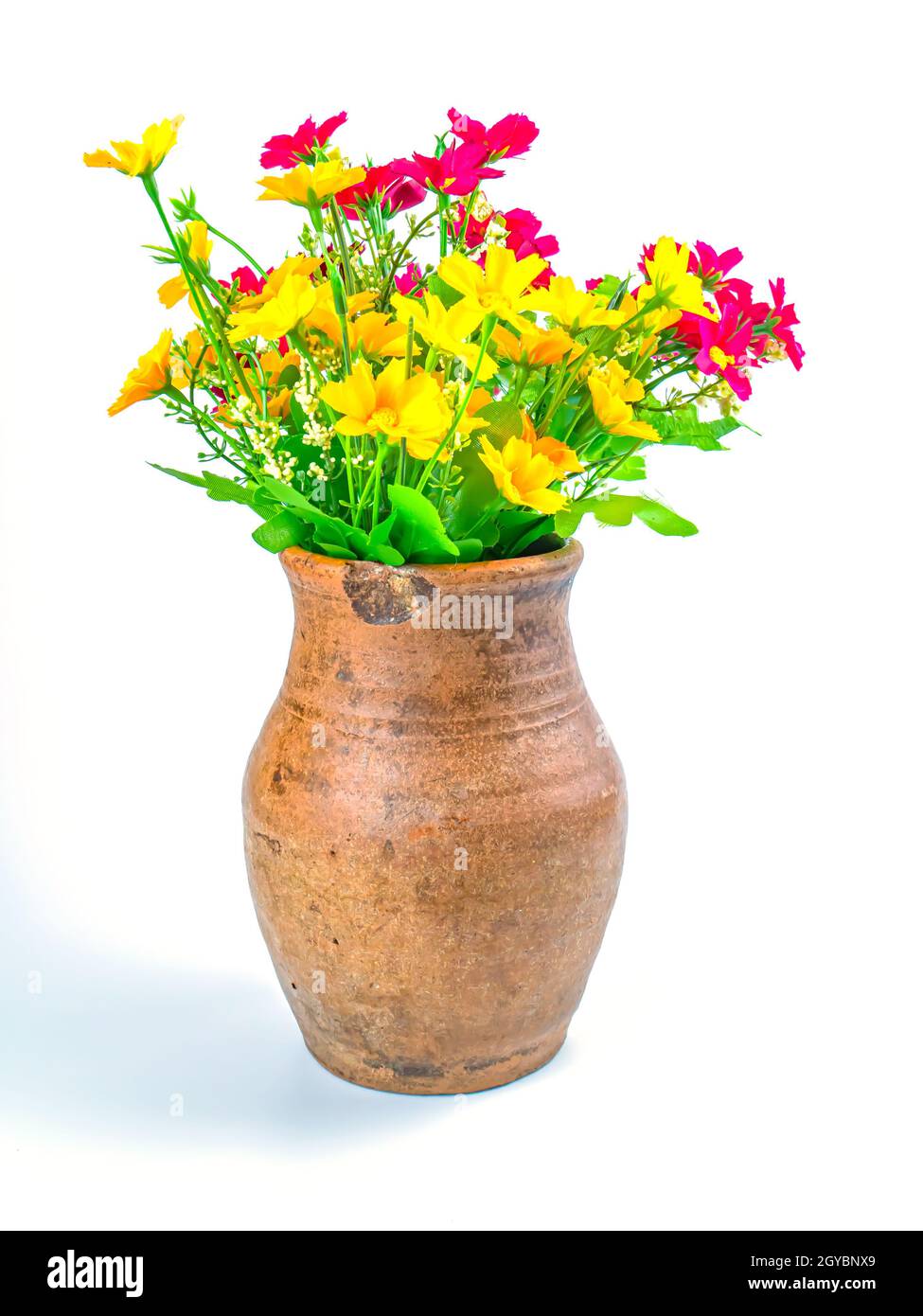 Un bouquet de fleurs artificielles dans un pot en argile. Bouquet de fleurs roses et jaunes. Vase en céramique. Faïence. Fait à la main. Arrière-plan blanc. Contexte i Banque D'Images