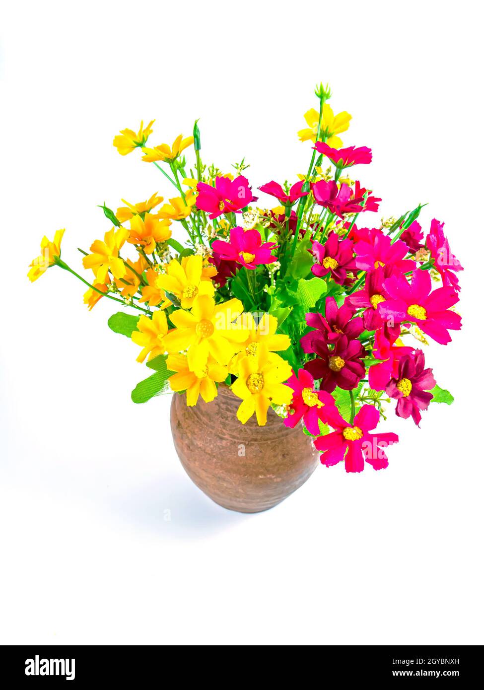 Un bouquet de fleurs artificielles dans un pot en argile. Bouquet de fleurs roses et jaunes. Vase en céramique. Faïence. Fait à la main. Arrière-plan blanc. Contexte i Banque D'Images