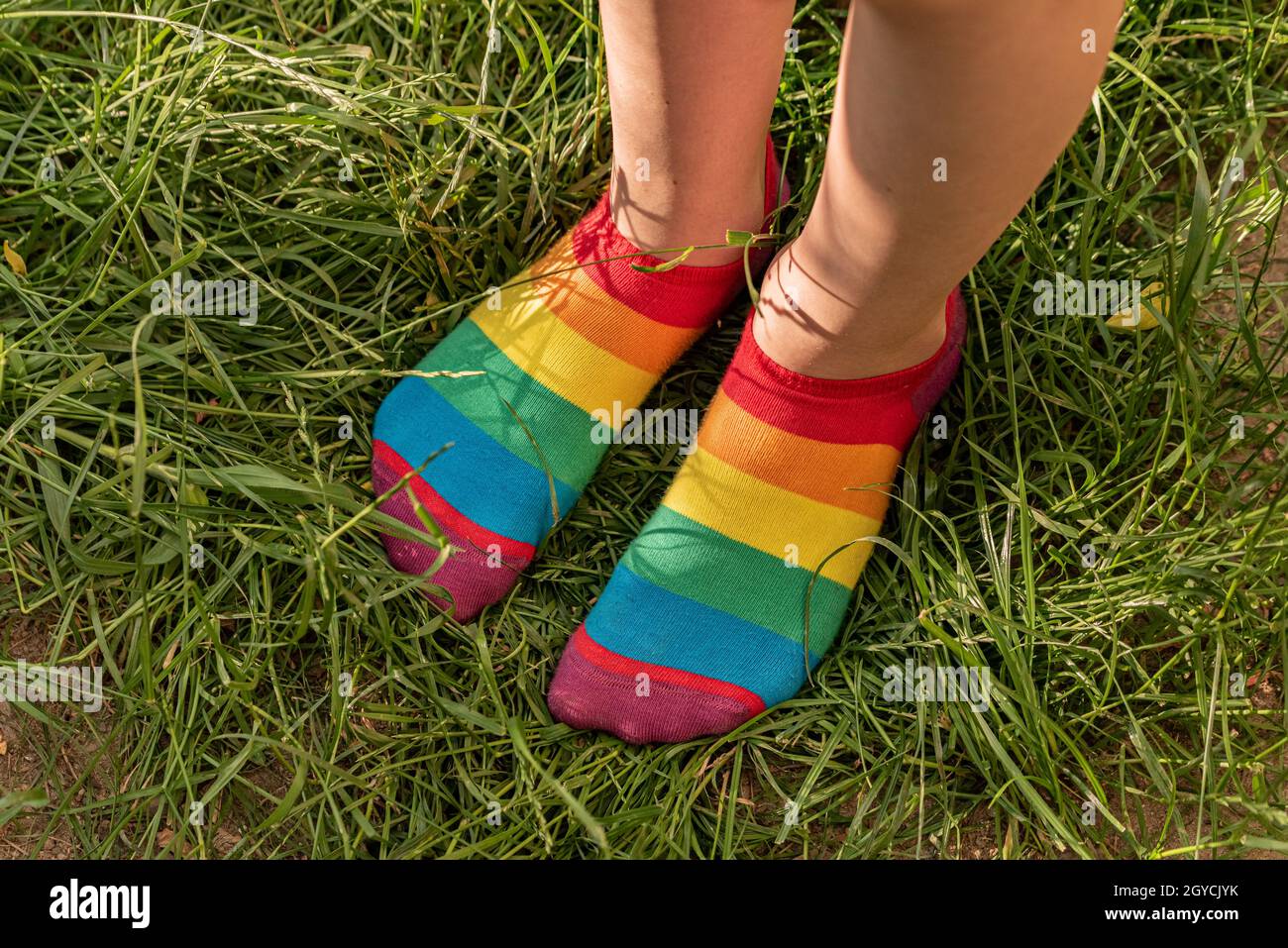 Chaussettes arc-en-ciel sur les pieds de la fille.Pieds d'enfant en  chaussettes colorées sur l'herbe verte Photo Stock - Alamy