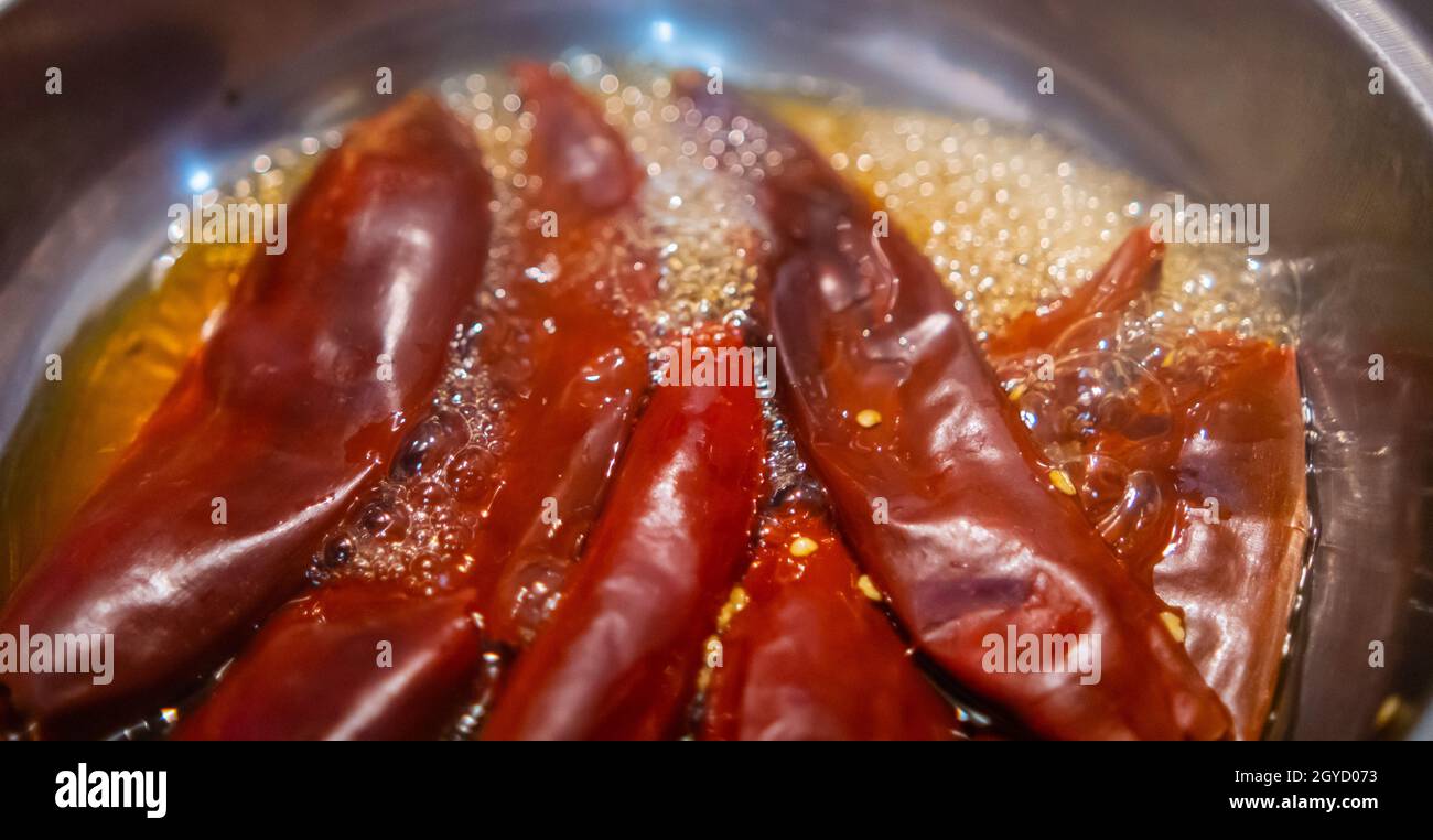 Poivrons rouges secs bouillant dans l'huile à l'intérieur de la casserole Banque D'Images