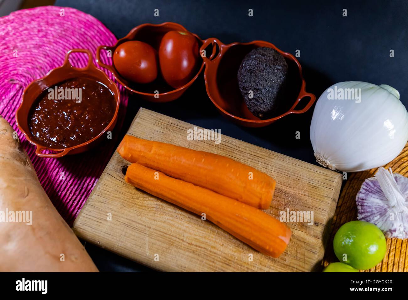 Carottes pelées sur la planche à découper entourées d'un plus grand nombre de légumes Banque D'Images