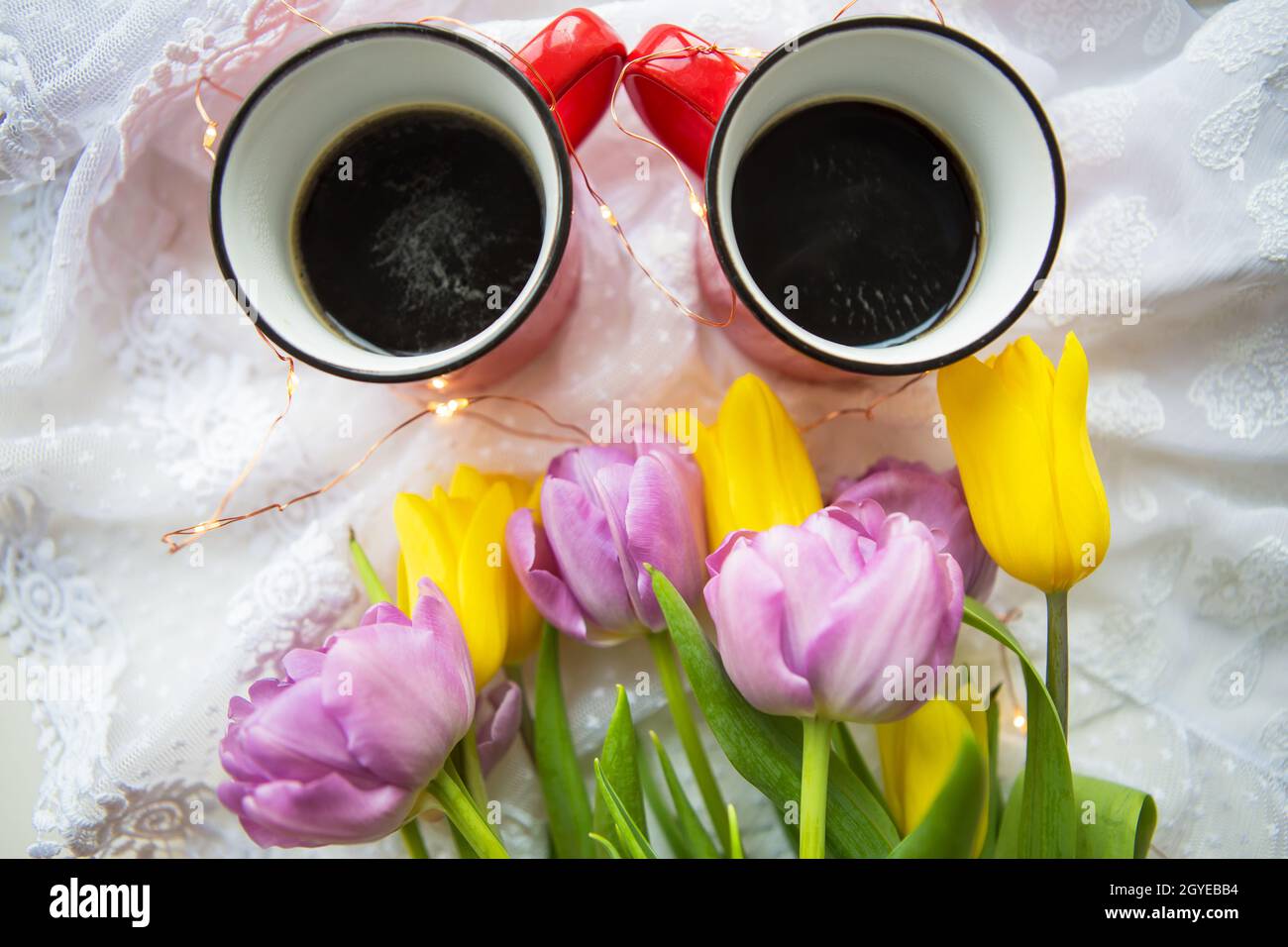 Beau matin, deux tasses de café et un bouquet de tulipes lumineuses. Banque D'Images