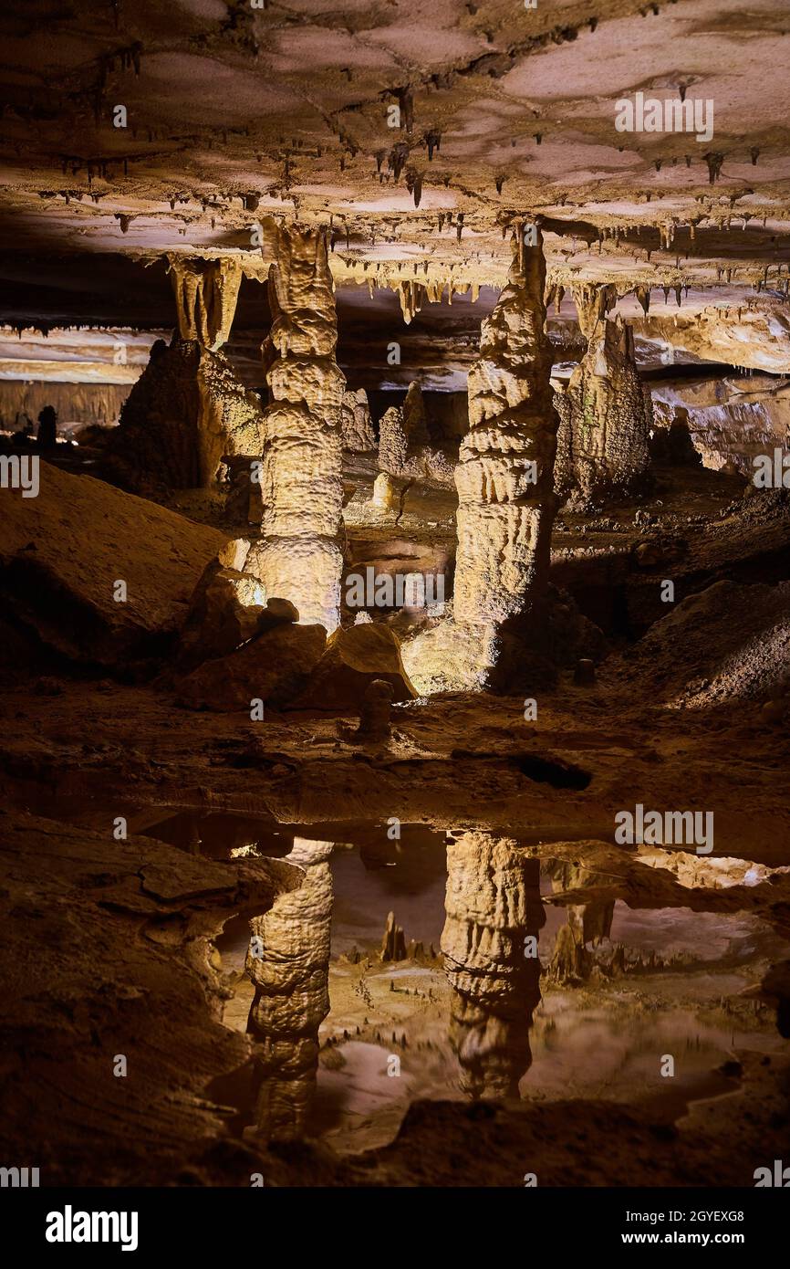 Paire majestueuse de stalagmites reflétant dans l'eau cristalline d'une grotte profonde Banque D'Images
