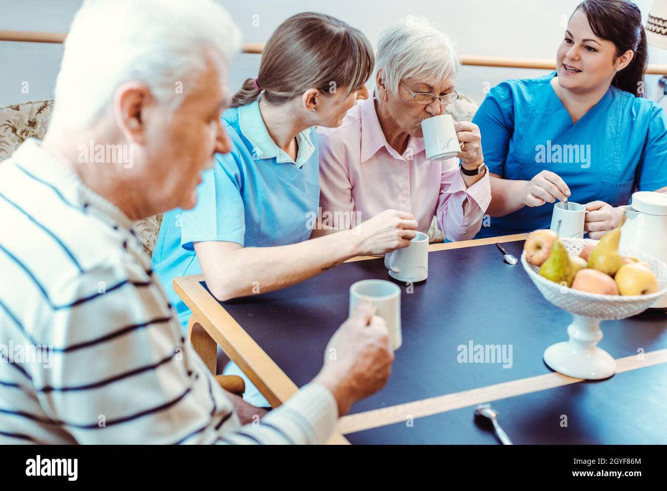 Les aînés et les aidants ayant du café dans le foyer de soins, manger et boire Banque D'Images