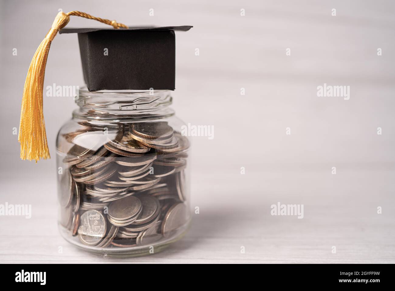 Chapeau d'écart de remise des diplômes sur les pièces d'argent dans le pot pour le fonds d'éducation; étude du concept d'apprentissage. Banque D'Images