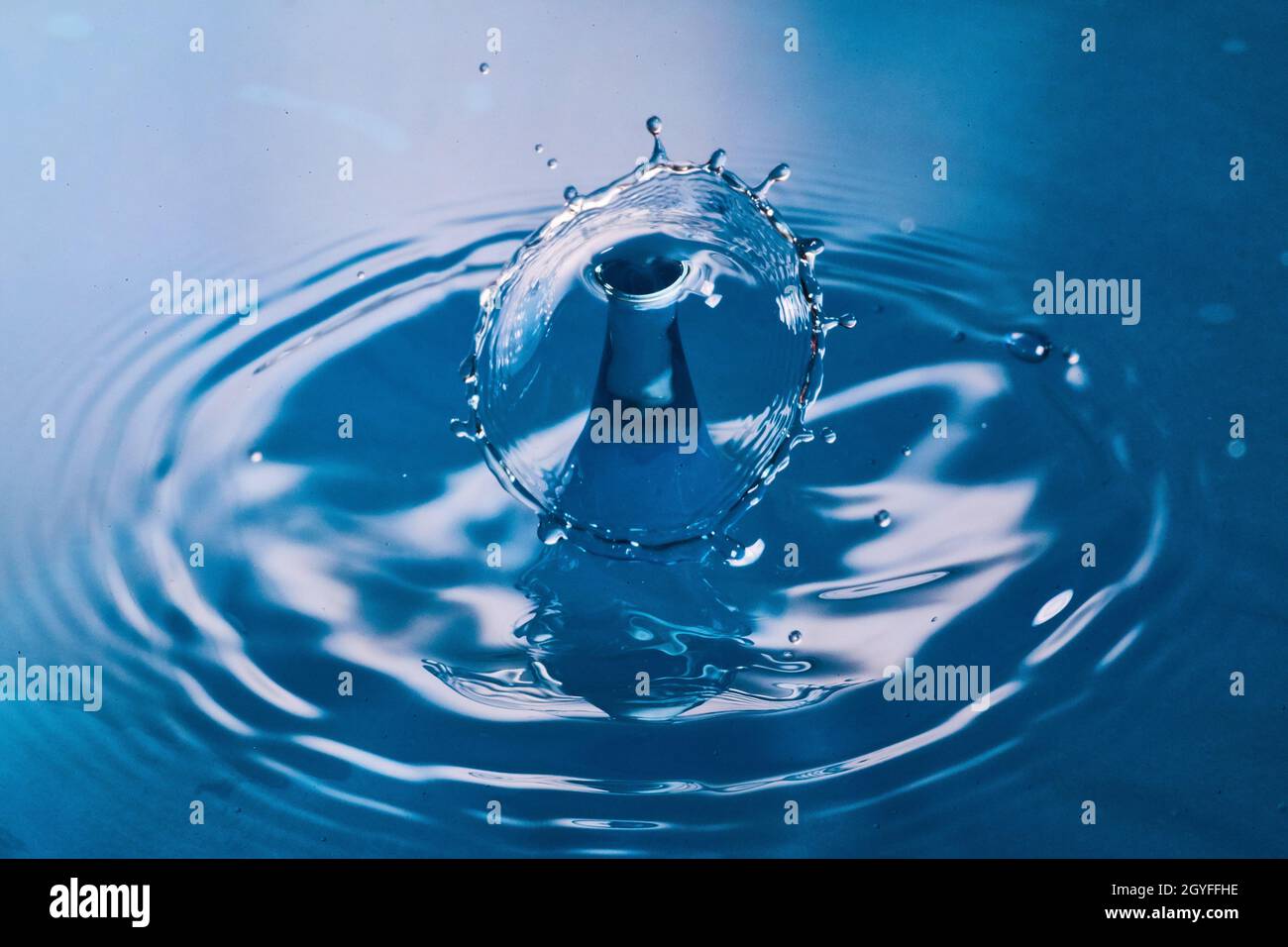 Deux gouttes d'eau entrent en collision sur une surface bleue propre Banque D'Images