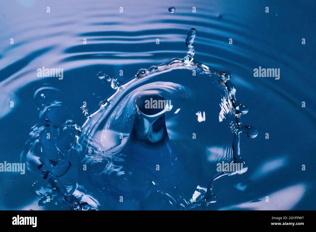 Des gouttes d'eau se brisent sur une surface d'eau bleue Banque D'Images