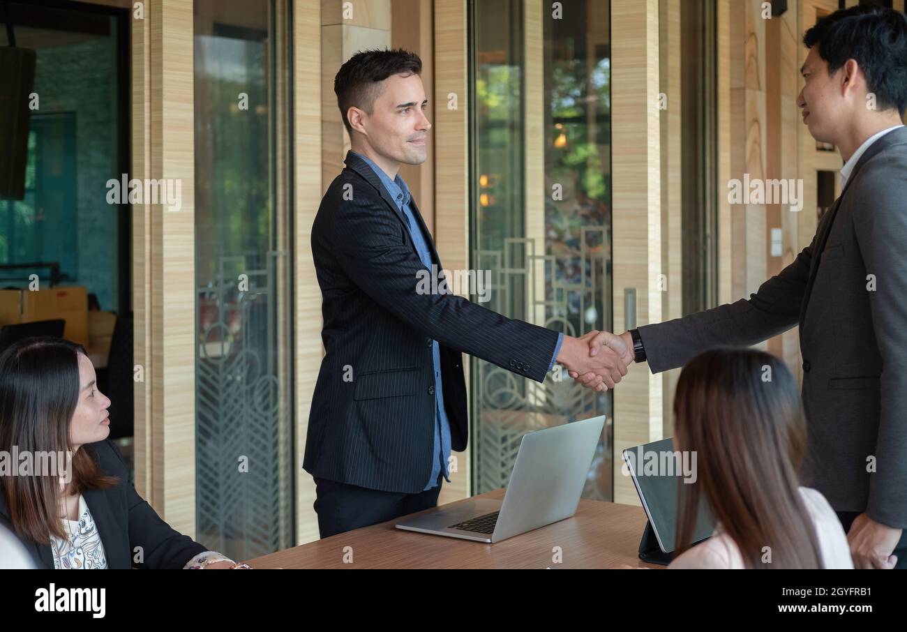 Les gens d'affaires de groupe sont en mesure de se mettre à la table de réunion au bureau en toute confiance.Les jeunes hommes d'affaires et les femmes d'affaires expriment leur accord Banque D'Images