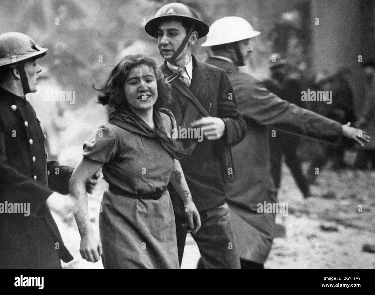 Des responsables de RAID aérien ont fait le poids d'une jeune femme en détresse dans la rue après un RAID aérien pendant le Blitz, Angleterre 1940. Banque D'Images