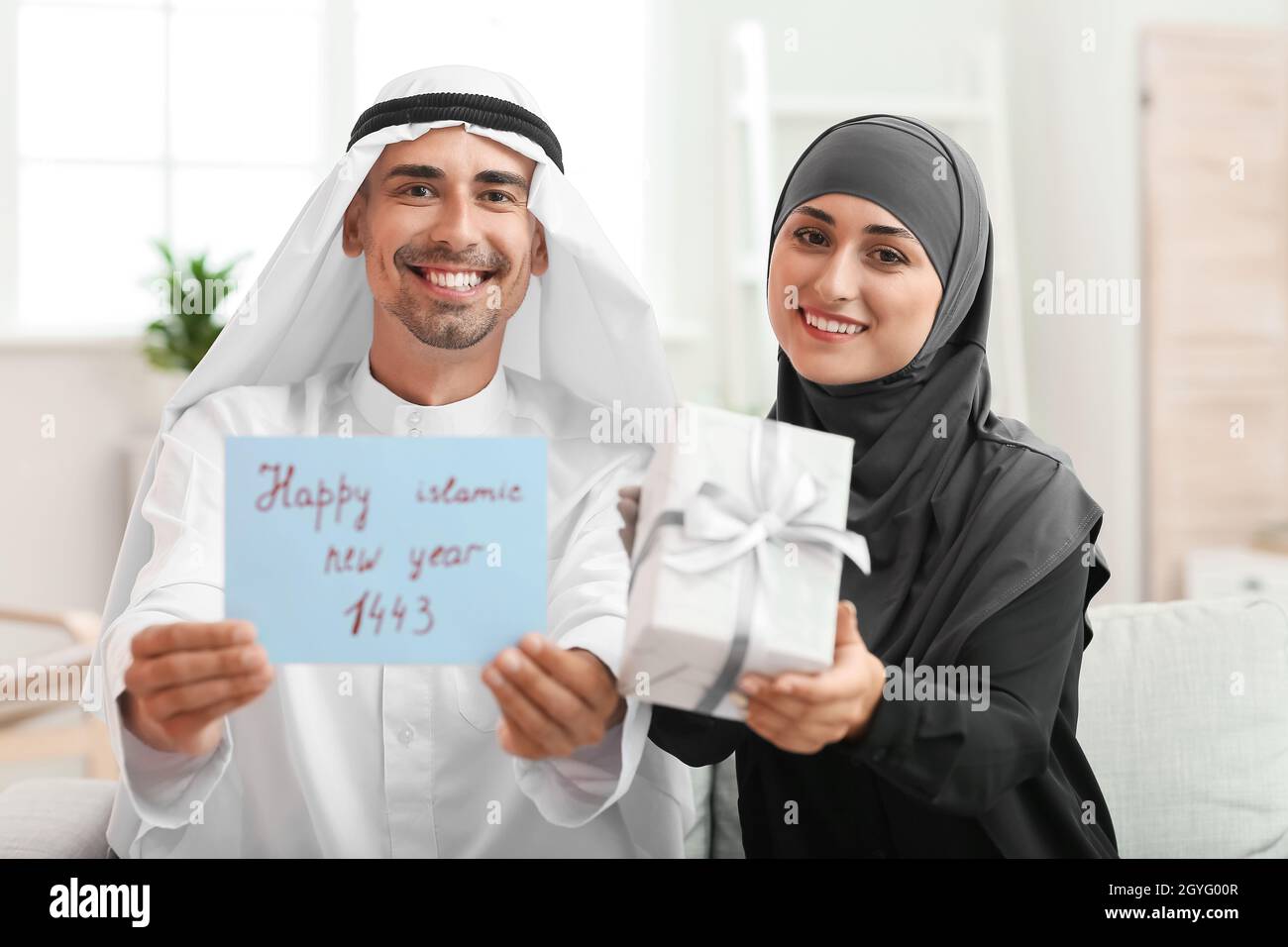 Jeune couple musulman avec cadeau et carte de vœux pour le nouvel an  islamique chez lui Photo Stock - Alamy
