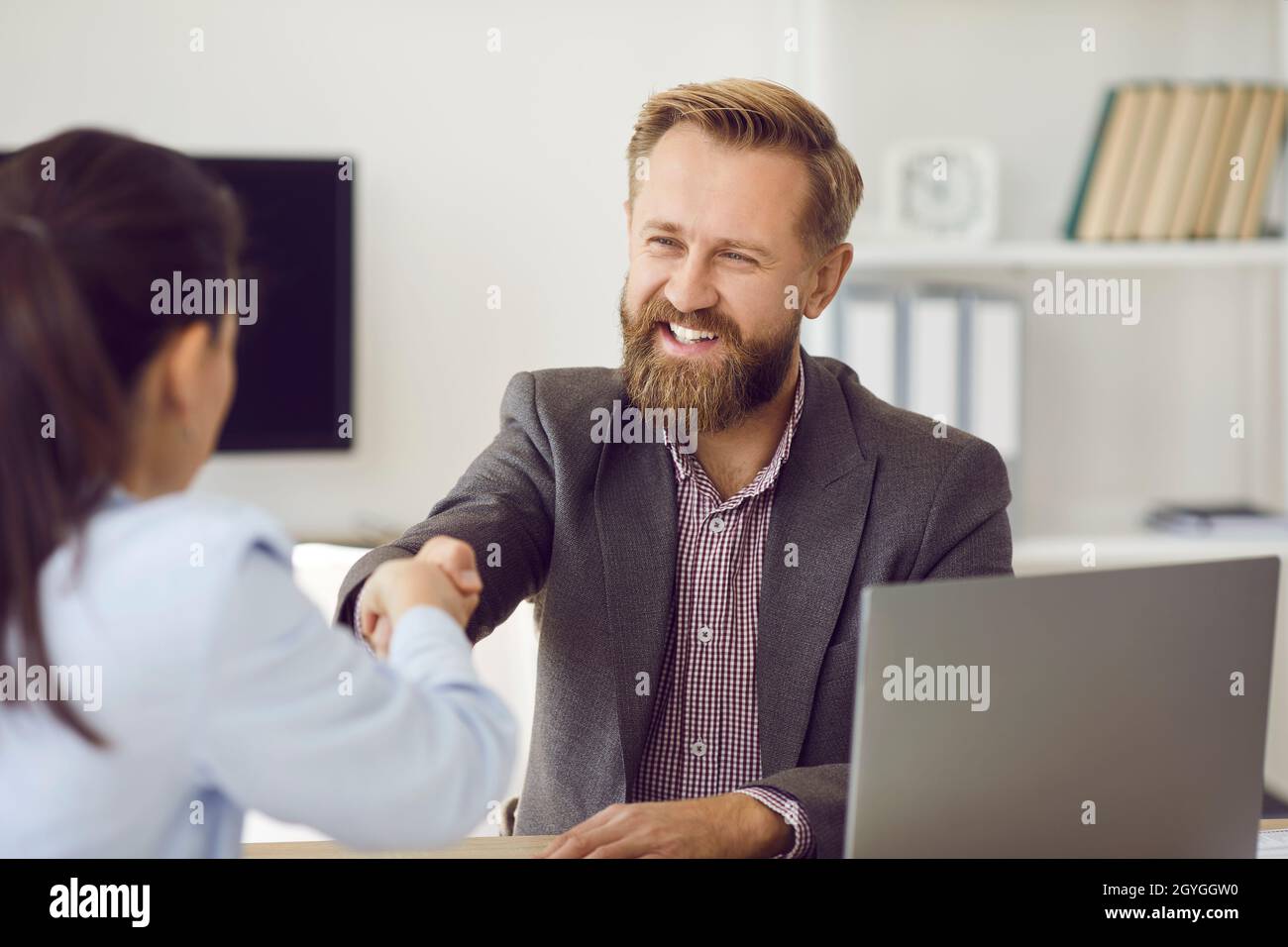 Un homme heureux souriant et se serrant la main avec une femme lors d'une réunion d'affaires au bureau Banque D'Images