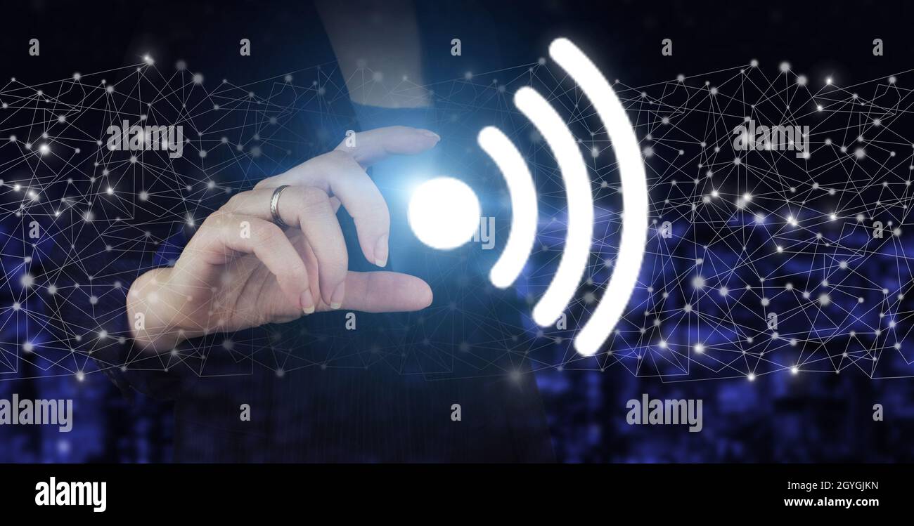 Concept de connexion réseau d'entreprise et Wi-Fi en ville.Main tenir l'hologramme numérique Wi Fi signe sur ville sombre flou arrière-plan Banque D'Images