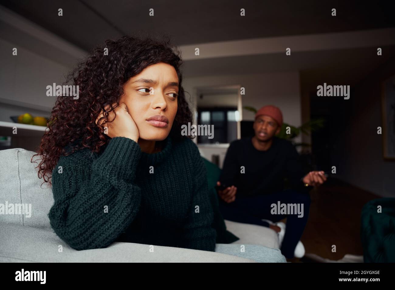 Une femme de race mixte s'est fâchée avec un petit ami tout en luttant sur le canapé dans un appartement moderne Banque D'Images