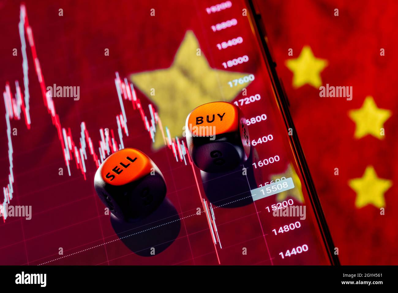 Dés avec les mots VENDRE ACHETER sur les bords.En arrière-plan le tableau de la chute de l'indice boursier des entreprises chinoises sur l'écran de smartphone. Banque D'Images