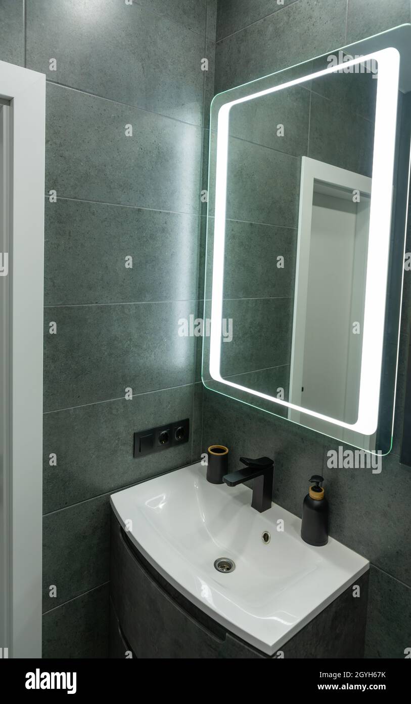 Décoration intérieure moderne et monochrome dans la salle de bains, coin lavabo en céramique blanche ou lavabo sous un grand miroir encadré Banque D'Images