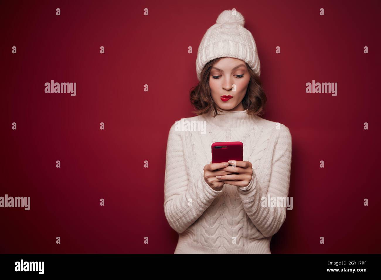 Femme joueur en pull tricoté dactylographiant dans le téléphone Banque D'Images