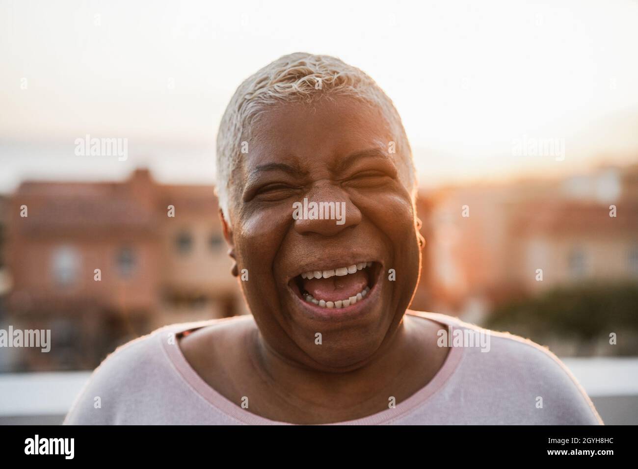 Bonne femme africaine senior souriant sur caméra en extérieur dans le Ville - Focus sur le visage Banque D'Images