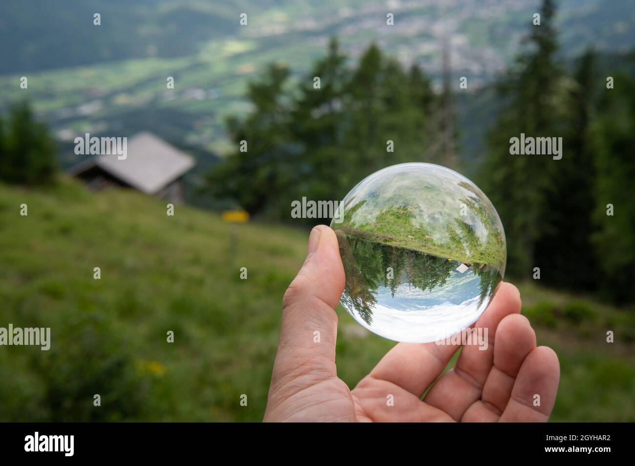 Main tenant la sphère de verre devant le pâturage, jour nuageux en été, alpes dans le Tyrol oriental (Autriche) Banque D'Images