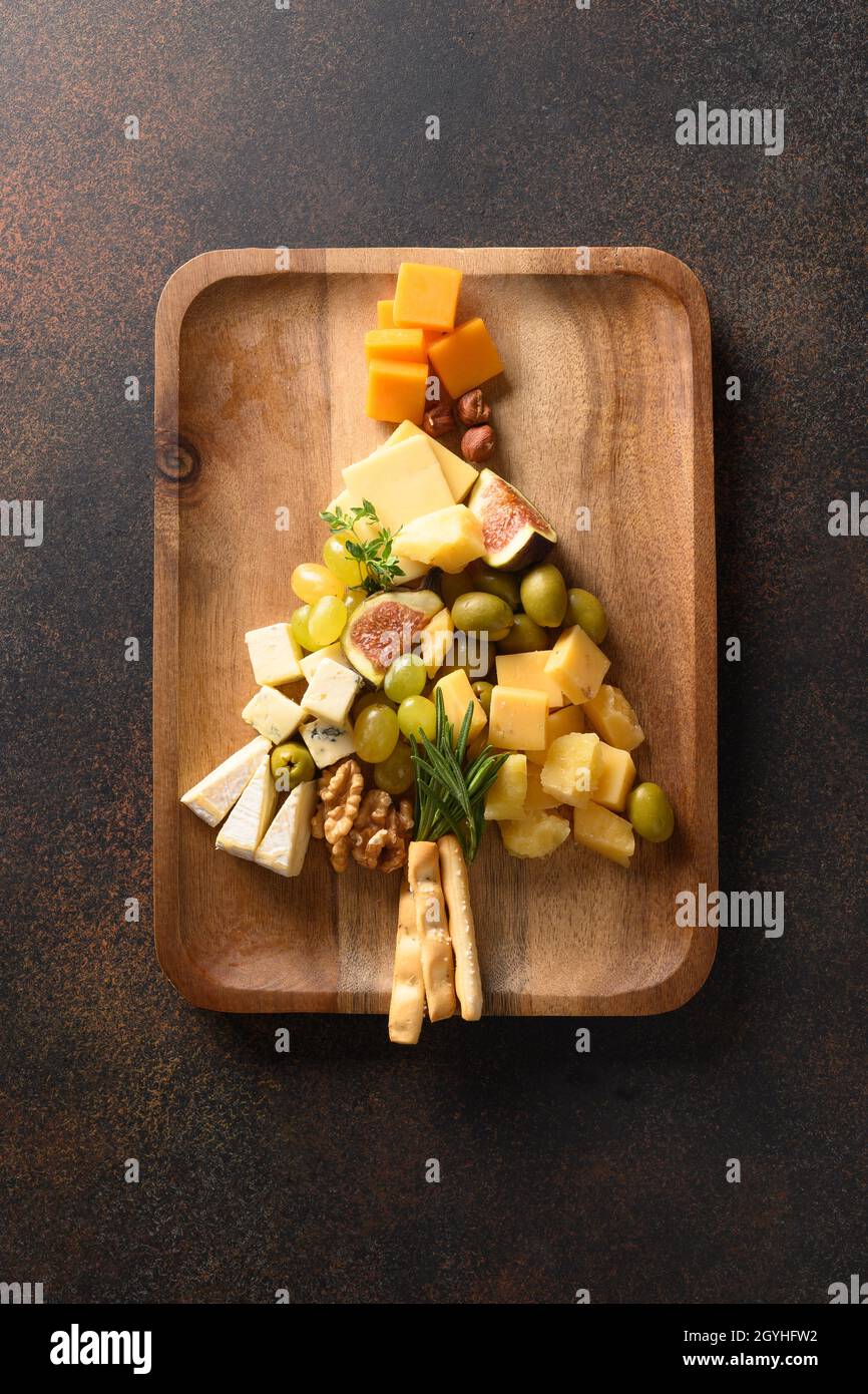 Assiette de fromage comme arbre de Noël avec différents fromages, raisins,  noix, olive, figues dans un plateau en bois sur un fond marron.Hors-d'œuvre  festif.Noël Hol Photo Stock - Alamy