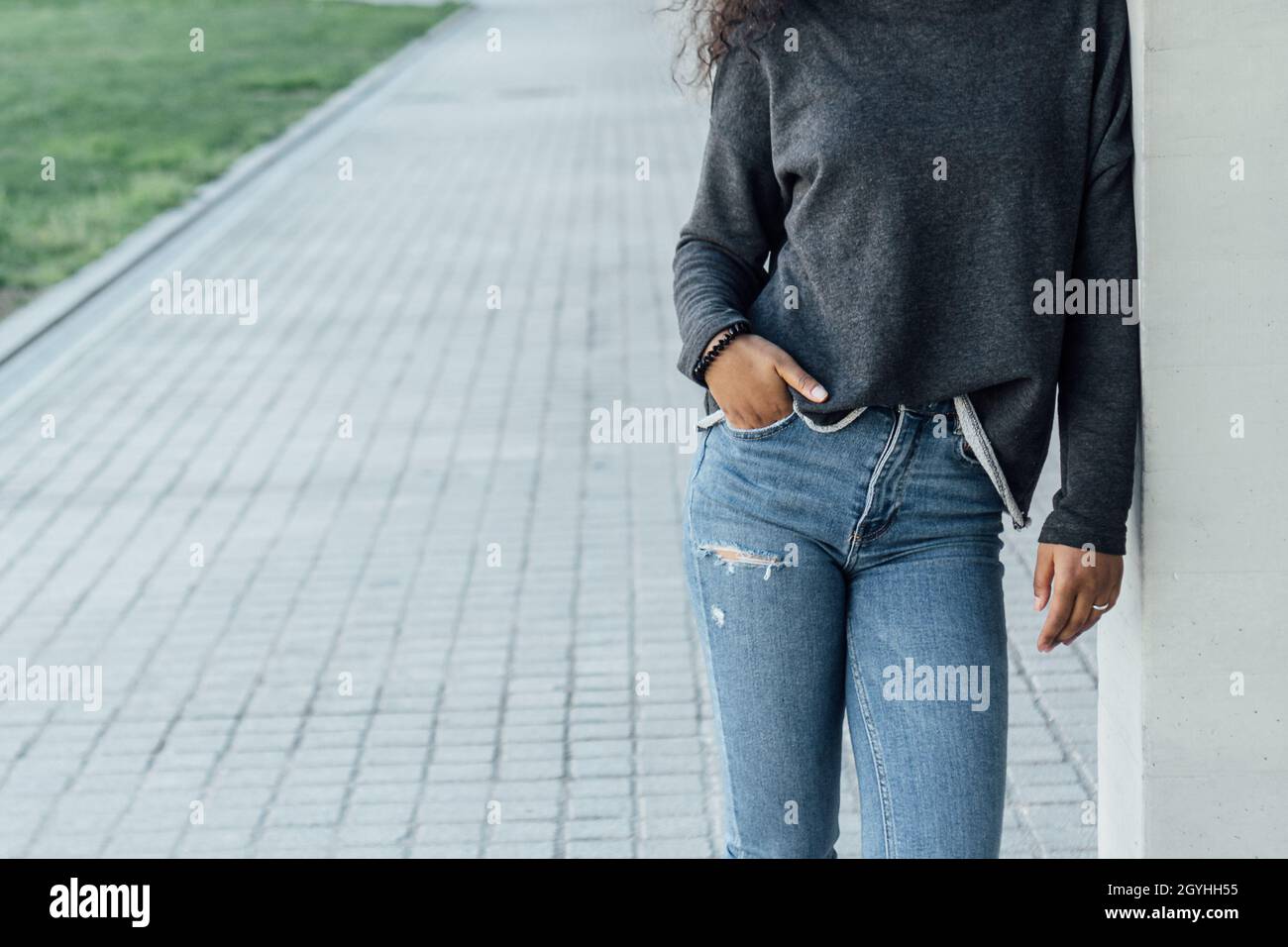 Jeune femme en vêtements de style urbain posant avec une main dans la poche à l'extérieur. Banque D'Images