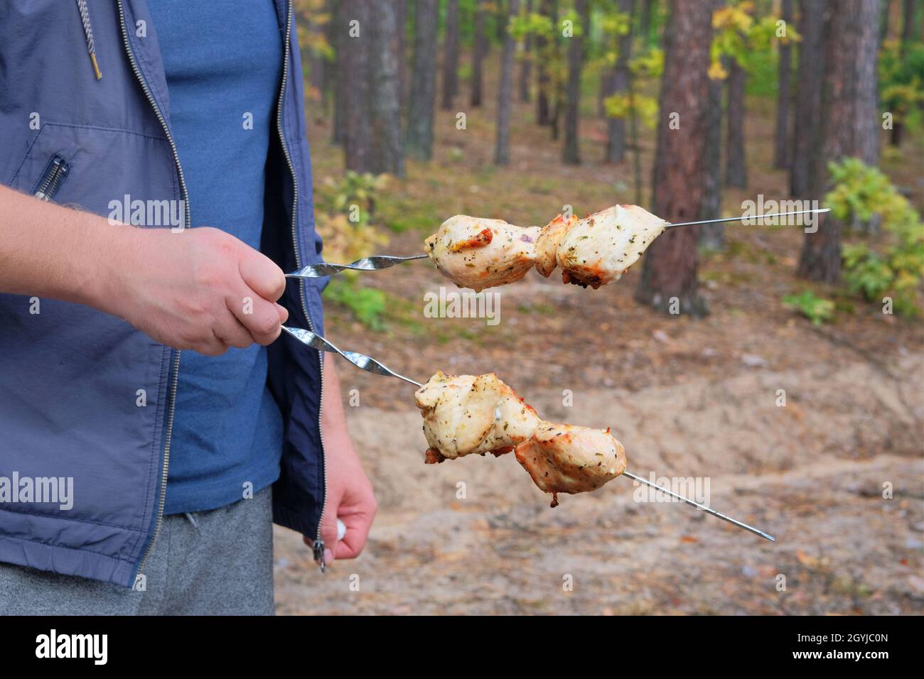 Viande grillée dans la main d'un homme dans la nature au camp.Faire frire le kebab sur la grille à l'air libre.La viande de poulet est frite. Banque D'Images