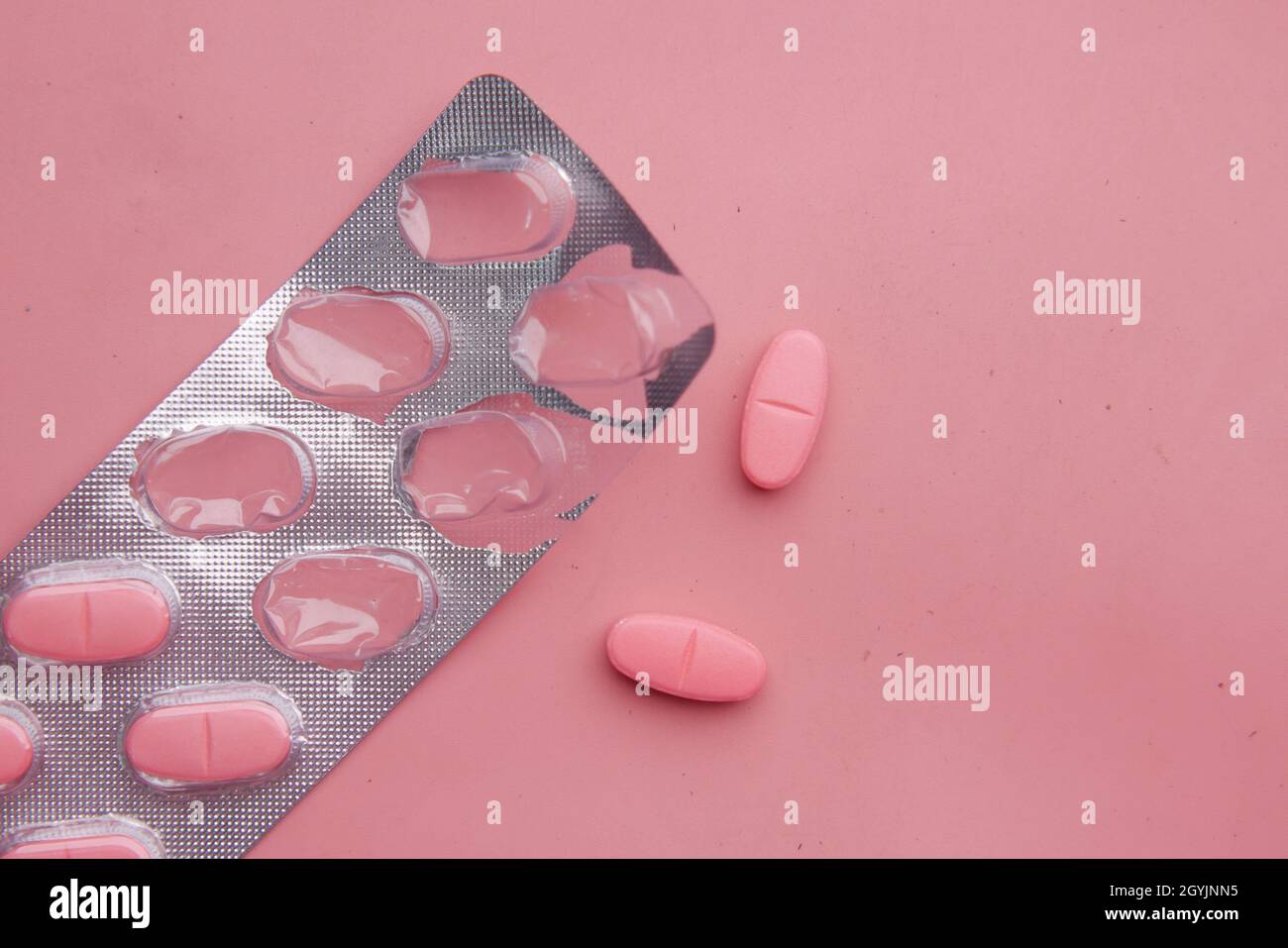 des pilules médicales de couleur rose débordent sur le rose Banque D'Images