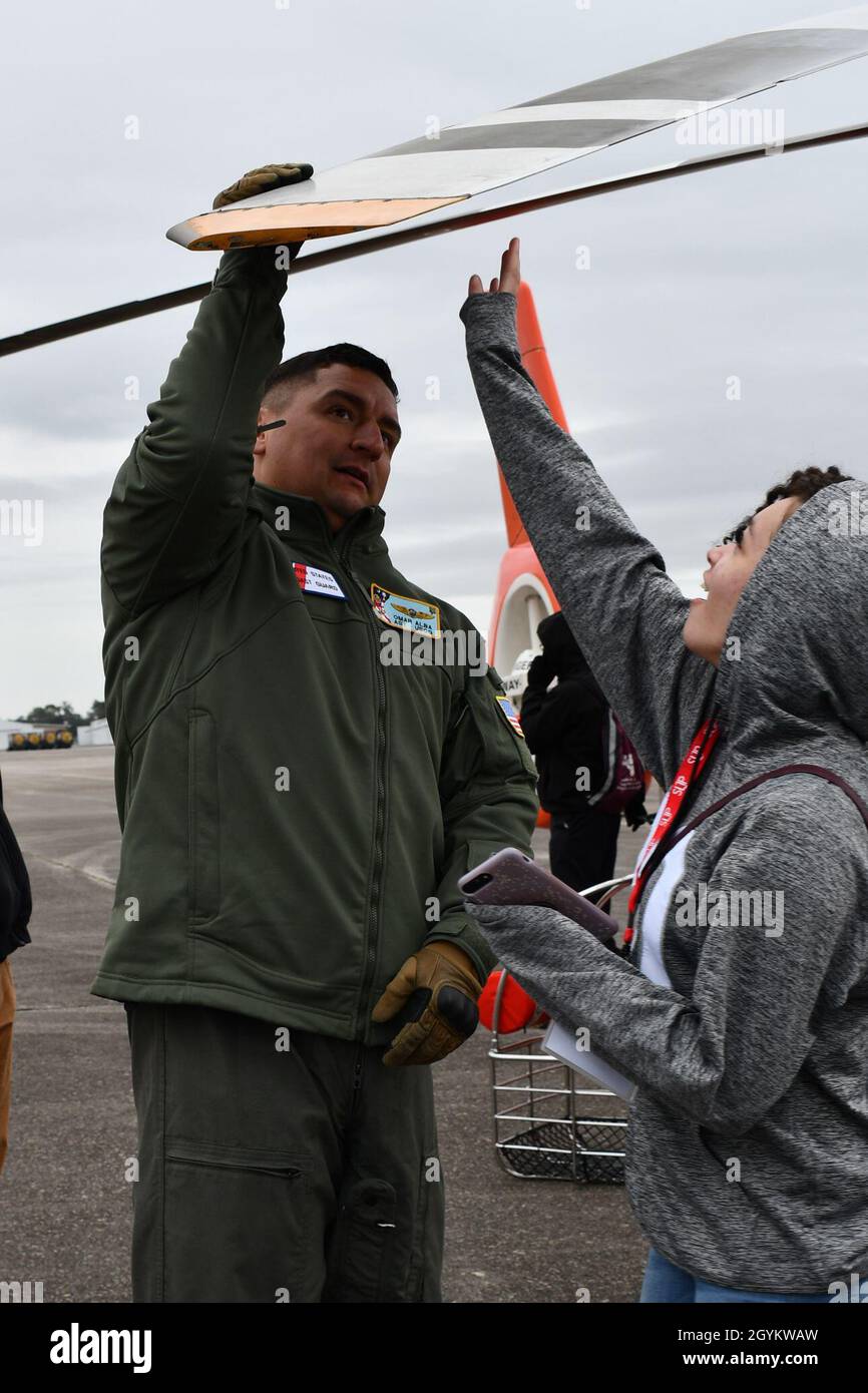 Nageur de secours de la Garde côtière des États-Unis, maître de Petty 2e classe Omar Alba qui est originaire d'El Paso, Texas et est affecté à la station aérienne de la Garde côtière des États-Unis-Savannah,Montre comment une lame à ailettes rotatives sur un hélicoptère MH65D peut se plier vers le haut et vers le bas à un groupe d'élèves du secondaire et de membres du corps professoral des écoles publiques du comté de Savannah-Chatham lors d'un symposium sur le leadership et les connexions parrainé par des leaders de l'industrie locale à Savannah, Géorgie, le 23 janvier 2020.Alba et une équipe de l'USCG Air Station Savannah ont parlé de leurs expériences et de l'hélicoptère MH65D dans le cadre de l'événement global conçu pour enha Banque D'Images