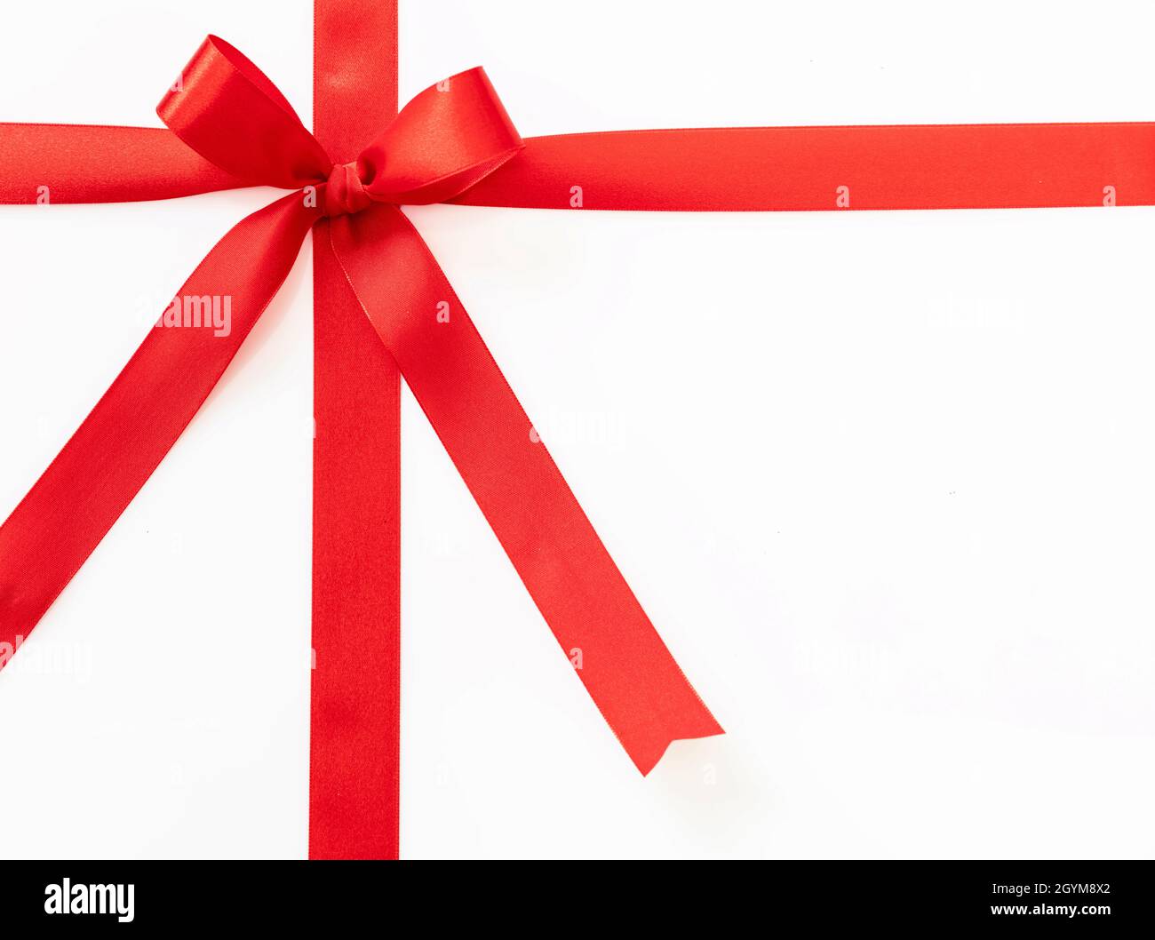Ruban cadeau avec noeud isolé sur fond blanc, Noël ou Valentin présente rouge satin décoration curly, élément design, vue du dessus. Banque D'Images