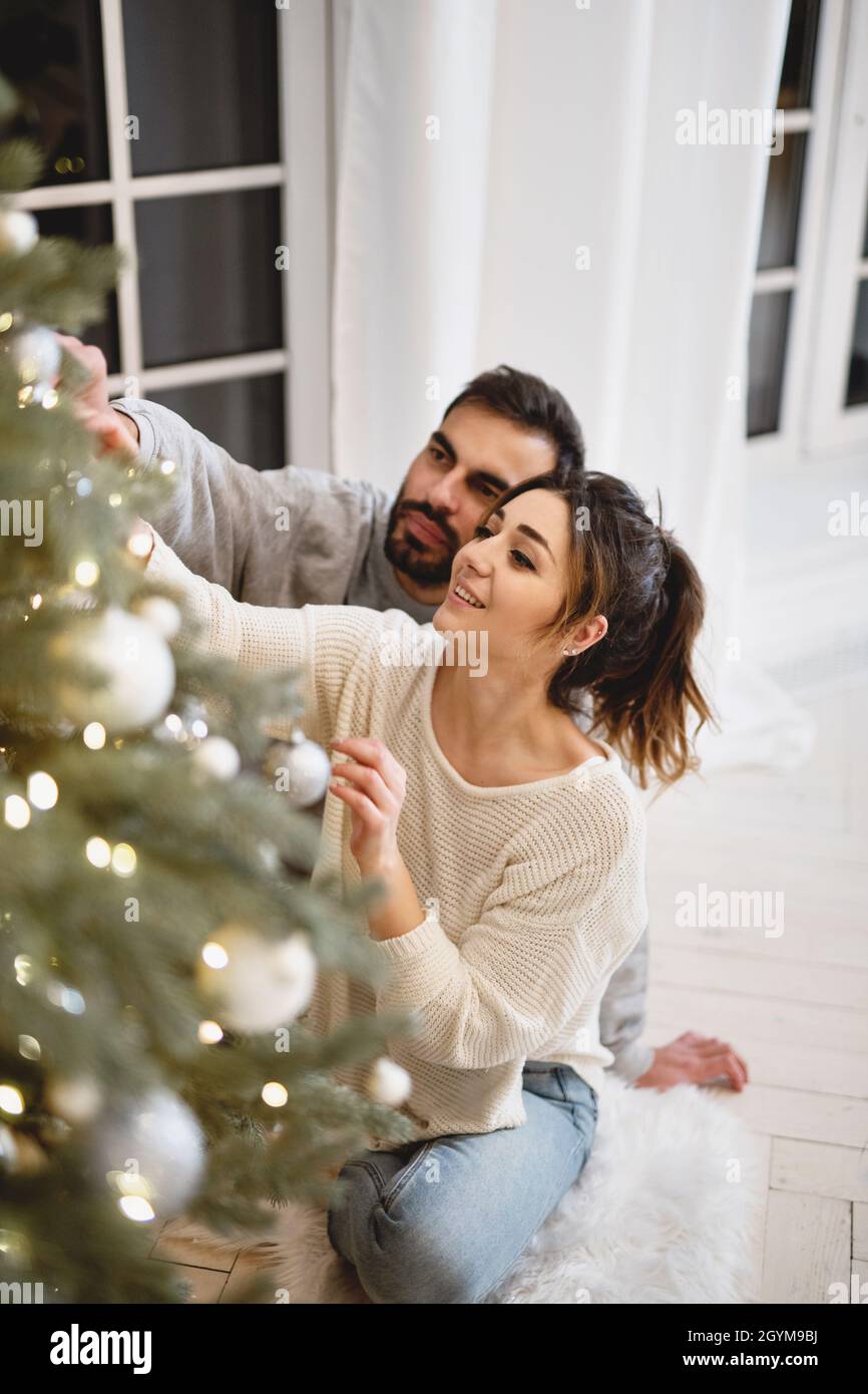 Couple charmant en amour décorant arbre de Noël. Banque D'Images