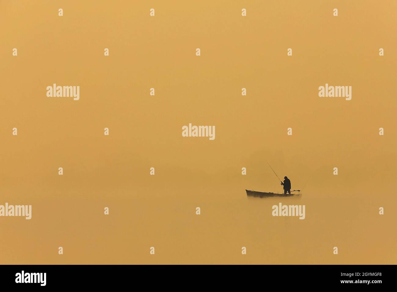silhouette d'un homme pêchant depuis le bateau au coucher du soleil, belles couleurs orange Banque D'Images