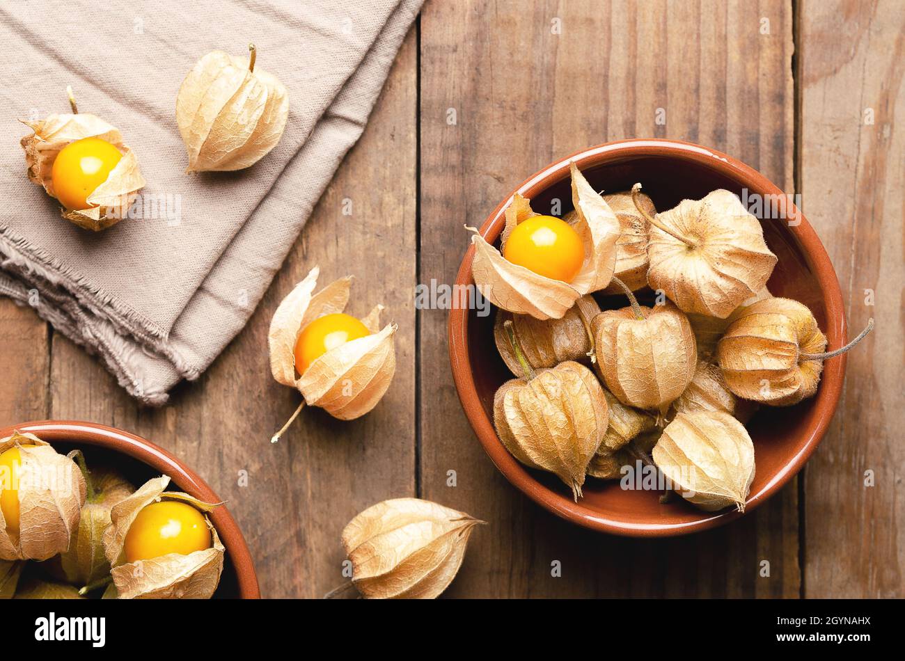 Physalis fruits péruviens dans des bols bruns sur fond de bois. Banque D'Images