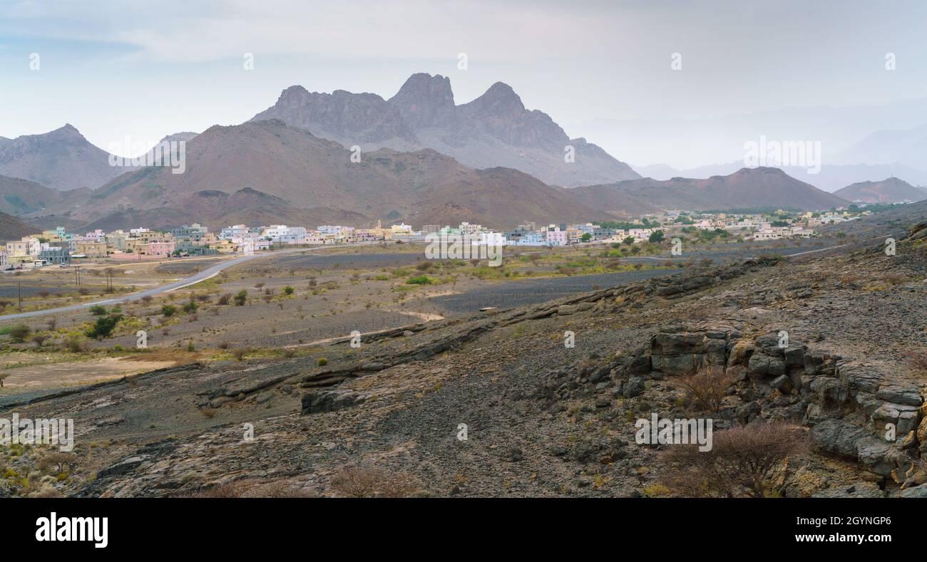 Petit village arabe dans un désert aride avec des montagnes à l'arrière.Vue depuis l'entrée de la grotte Al Hoota à Oman.Jour de printemps brumeux en arabe Banque D'Images