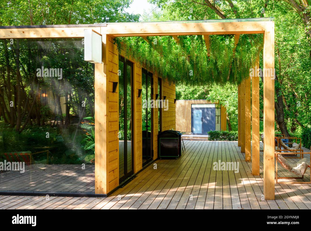 Couvert de plantes vertes, beau paysage de café extérieur dans le parc.Décor moderne du toit de la maison.Aménagement paysager confortable avec bois et v Banque D'Images