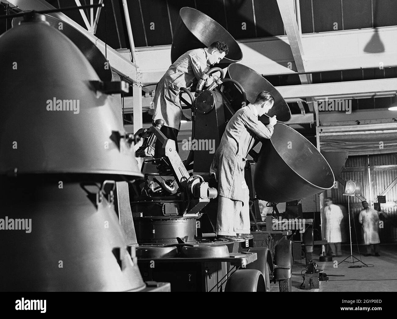 Les ouvriers ajustent un ensemble de paraboloïdes dans un détecteur sonore destiné à être utilisé par des batteries anti-aériennes qui protègent l'Angleterre, dans une usine quelque part en Angleterre, le 30 juillet 1940. Banque D'Images