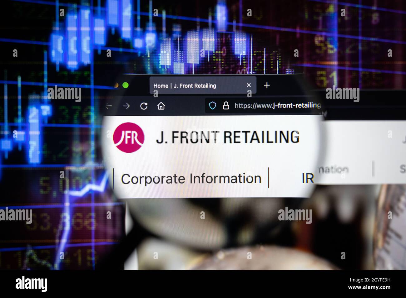 J. logo de la société de vente au détail sur un site Web avec des graphiques de marché boursier flous en arrière-plan, vu sur un écran d'ordinateur à travers une loupe. Banque D'Images