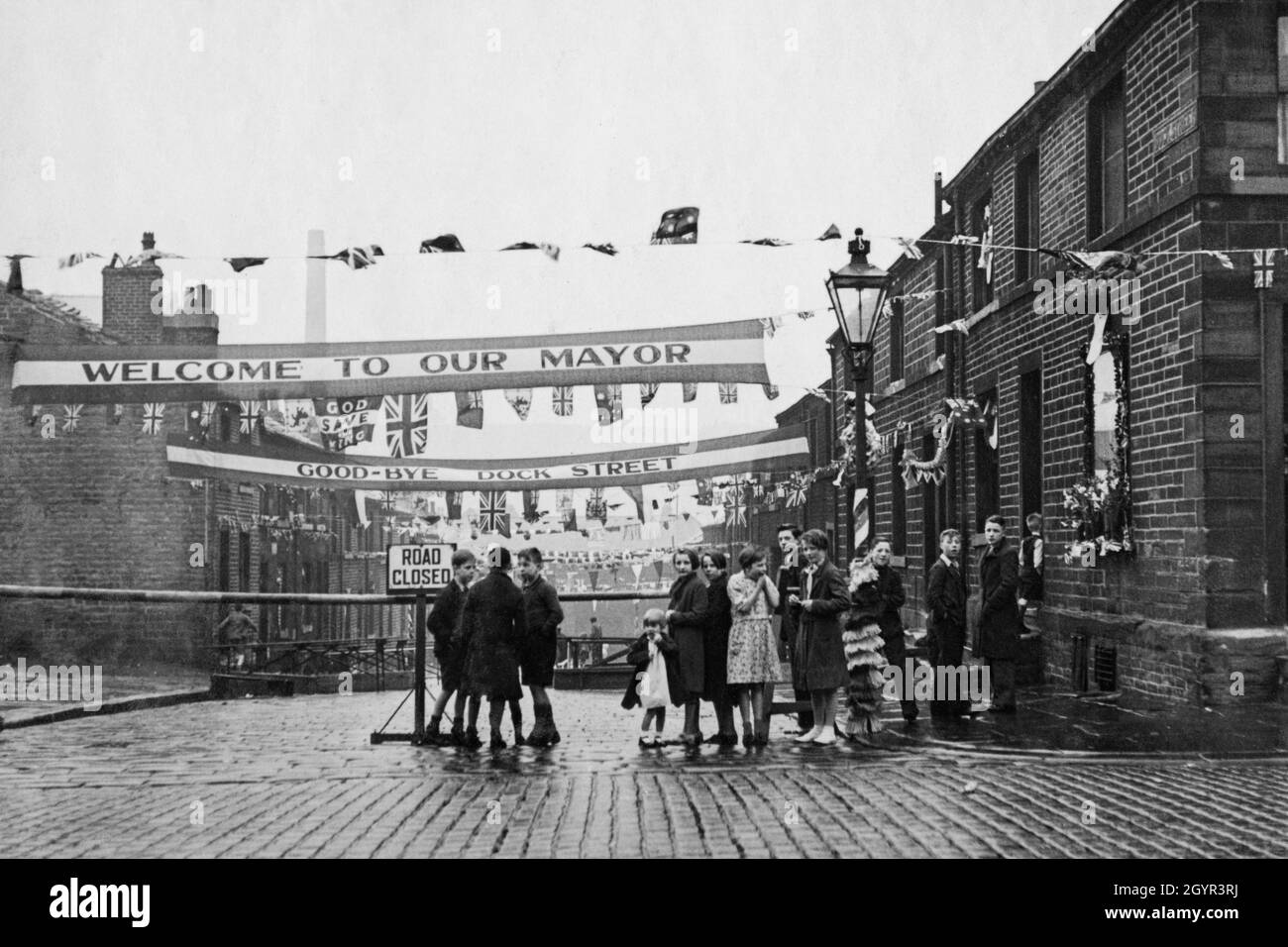 La bannière « God Save the King », Union Jacks et Bunkting décorent une rue à Huddersfield, dans le Yorkshire, en Angleterre, pour célébrer le couronnement du monarque britannique, le roi George VI, le 12 mai 1937 Banque D'Images