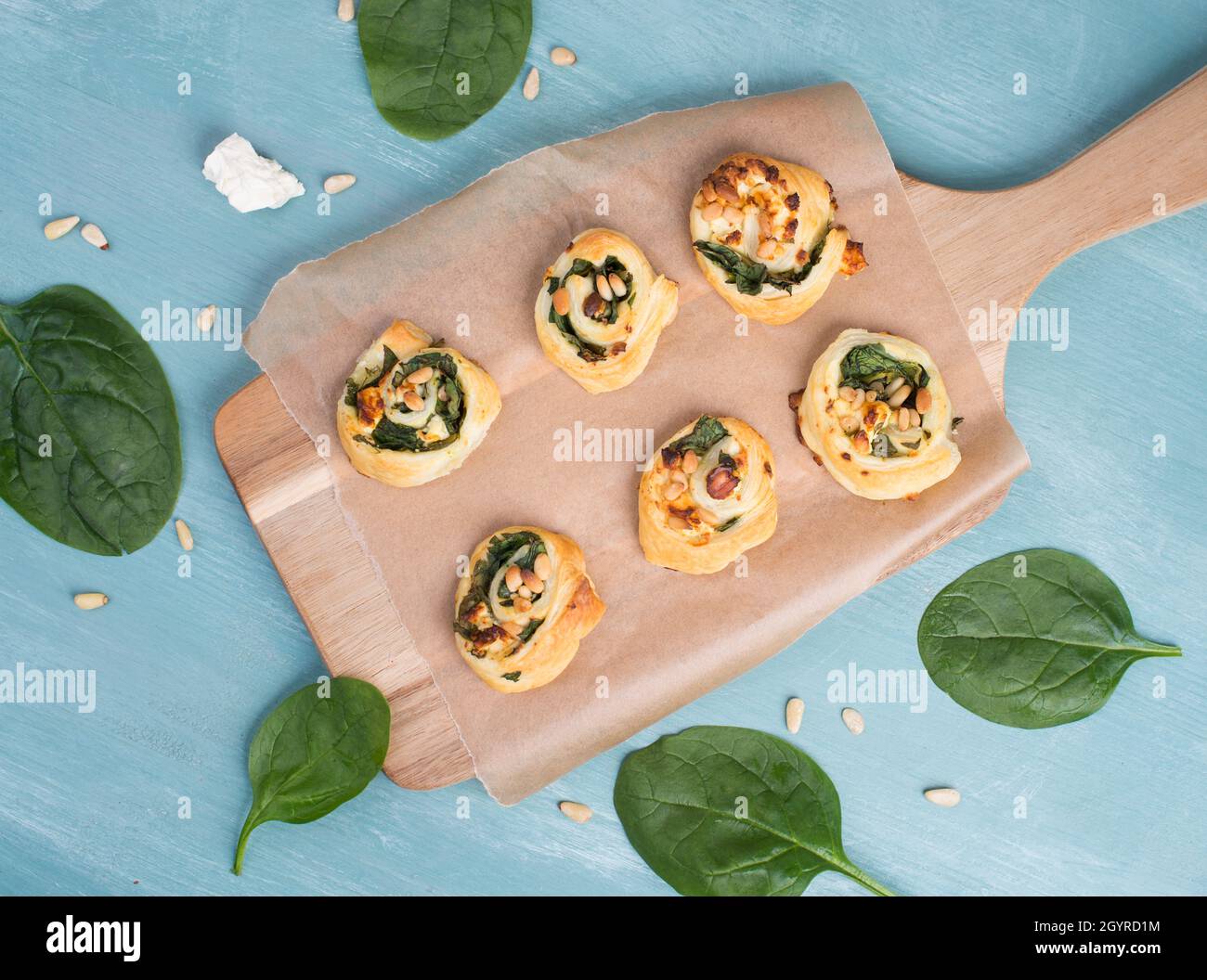 Pâte feuilletée aux épinards et au fromage feta, enroulée en spirales, fraîche du four, fond bleu Banque D'Images