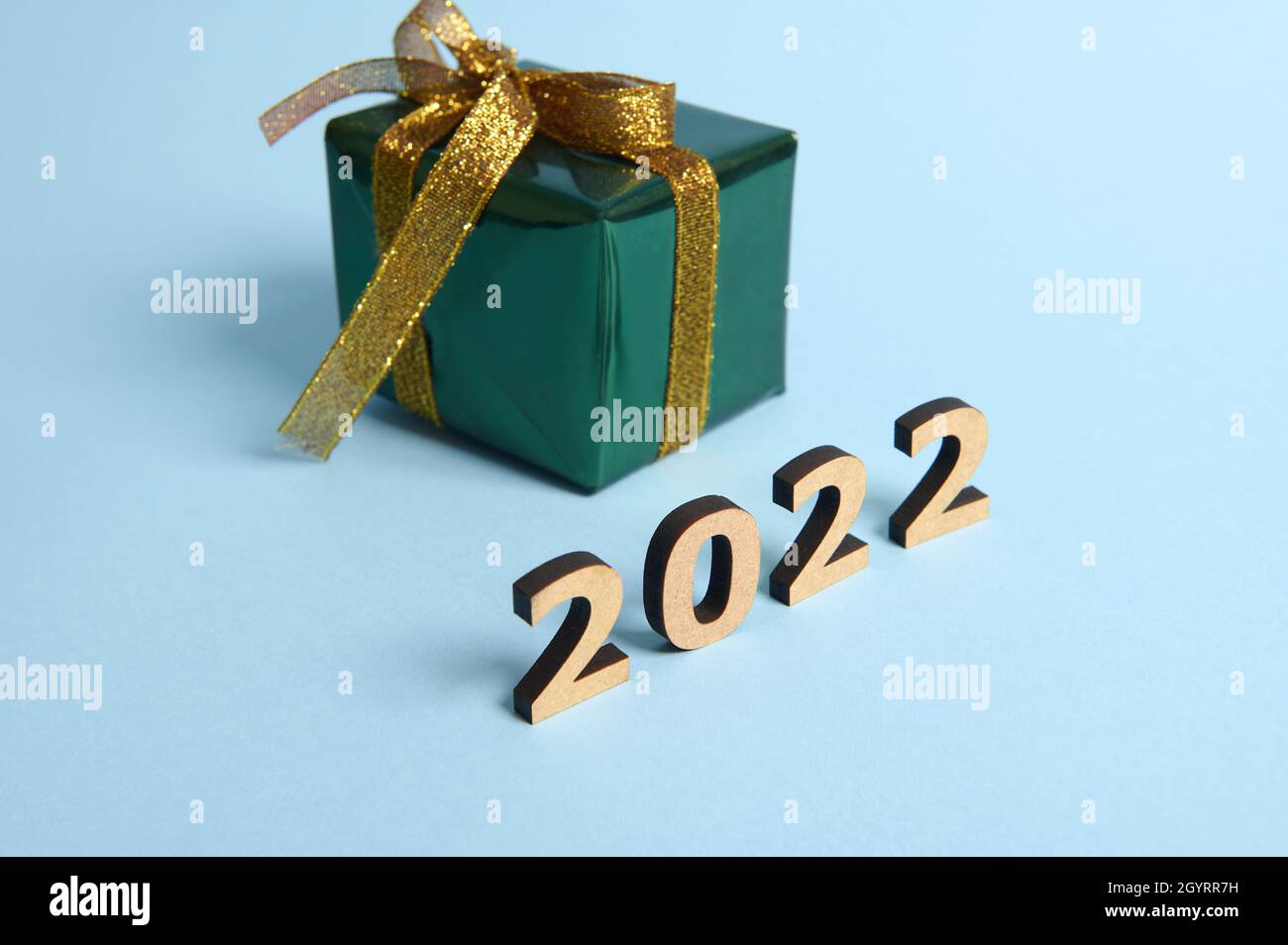 Cette boîte est enveloppée de papier cadeau brillant vert brillant et de  ruban doré et d'un noeud sur fond bleu avec des numéros en bois année  2022.Noël, ne Photo Stock - Alamy