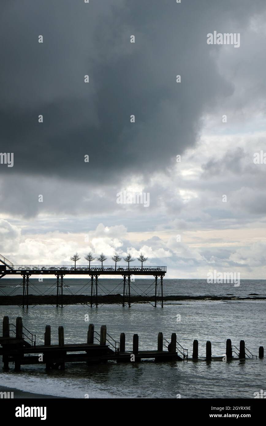 Nuages sombres au-dessus de la Royal Pier, Aberystwyth, pays de Galles, Royaume-Uni.Imitation d'arbres décoratifs à l'extrémité de la jetée Banque D'Images