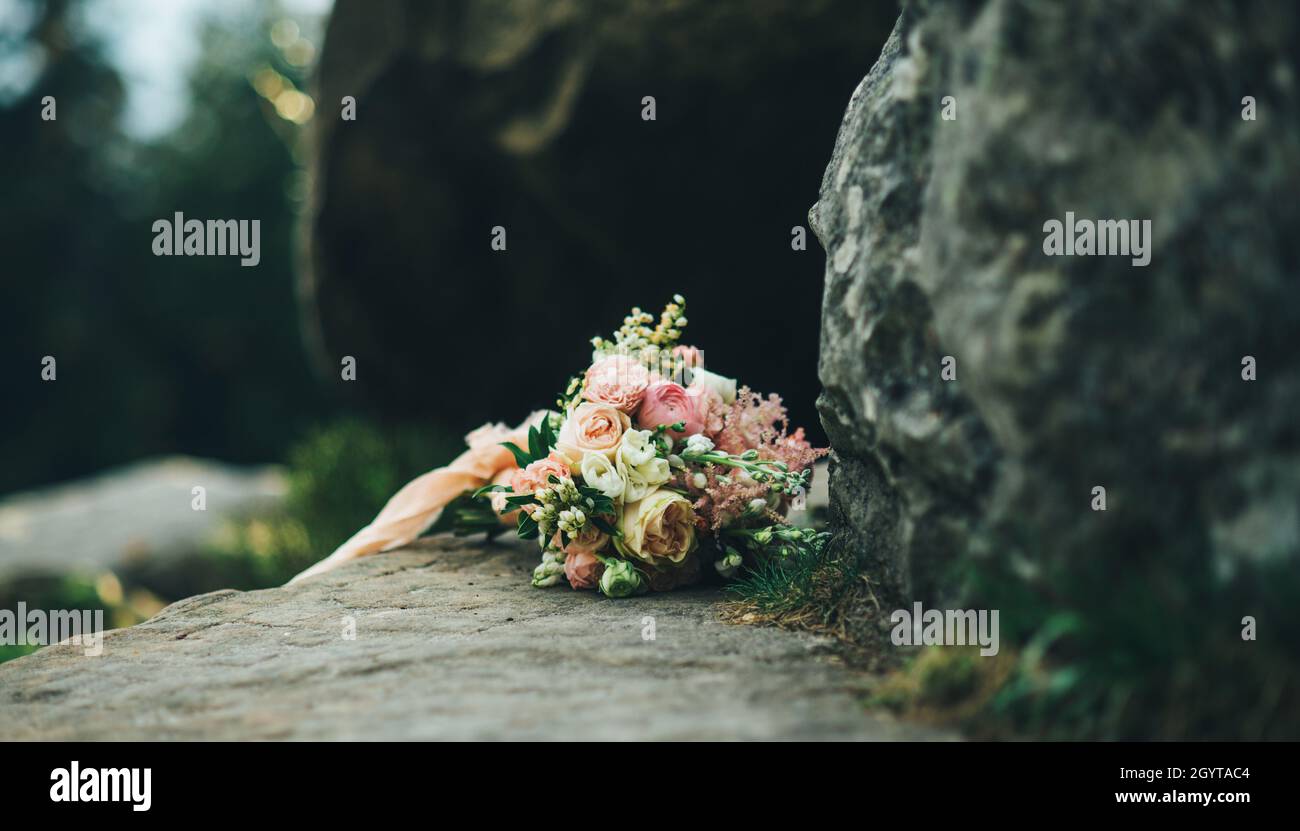 beau bouquet de mariage blanc beige et rose fleurs pourpres est posé sur la pierre dans les montagnes Banque D'Images