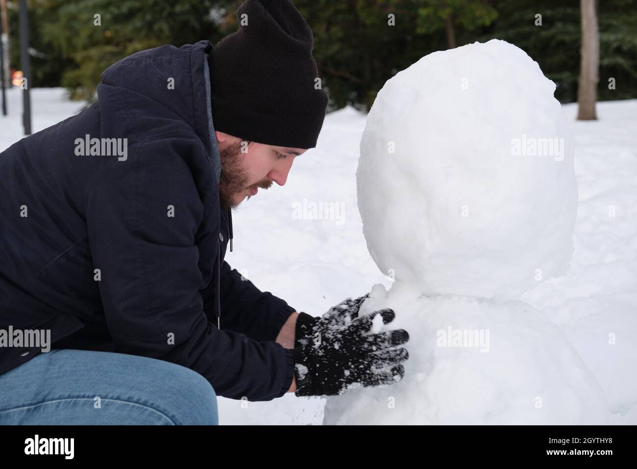 Un jeune homme de race blanche fait un bonhomme de neige Banque D'Images