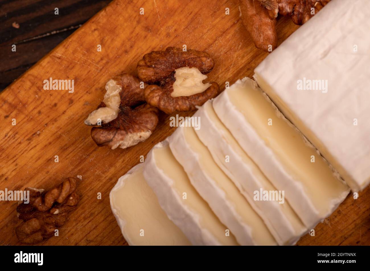 Tranches de camembert et de noix sur une planche à découper en bois, gros plan, mise au point sélective Banque D'Images
