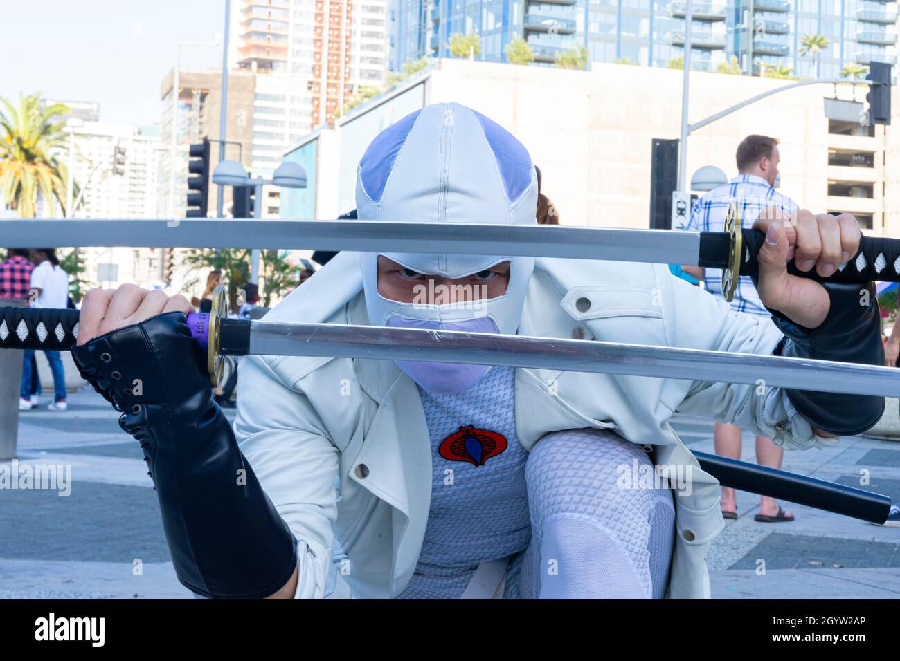 Participant cosplayer présentant le ninja guerrier japonais thoug en vêtements blancs avec une coiffe et deux katanas au Comic con à Los Angeles Banque D'Images