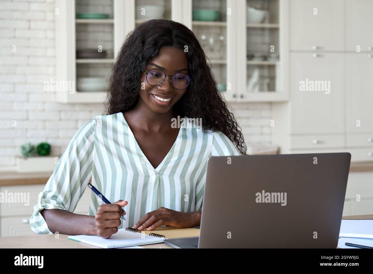 Bonne femme noire apprenant à la maison regardant le webinaire sur ordinateur portable. Banque D'Images