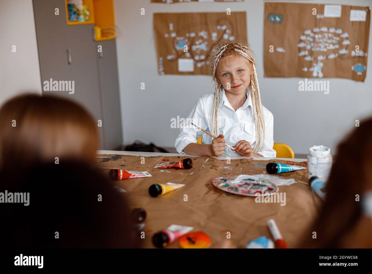 Petite fille mignonne assise à un bureau lors d'une leçon de dessin Banque D'Images