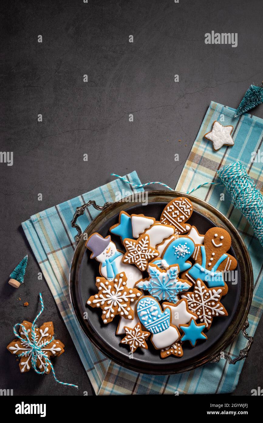 Biscuits de Noël à pain d'épice glacé bleu et blanc sur plateau sur une serviette avec ficelle.Arrière-plan gris foncé.Vue de dessus avec espace de copie Banque D'Images